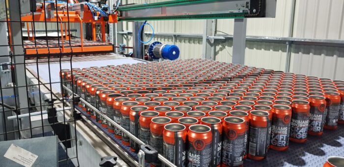 Empty orange cans being depalletised onto high level conveyor