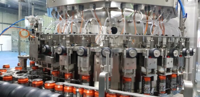 Orange Williams Brothers Cans being filled on an Electropneumatic filler